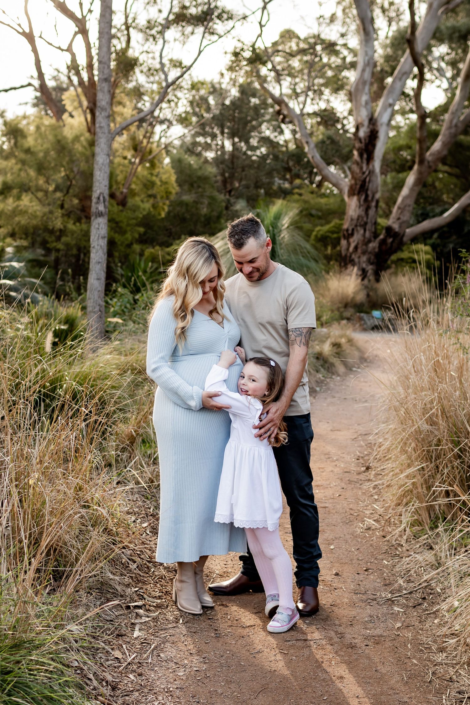 Family shares tender moment together on sunlit nature trail.