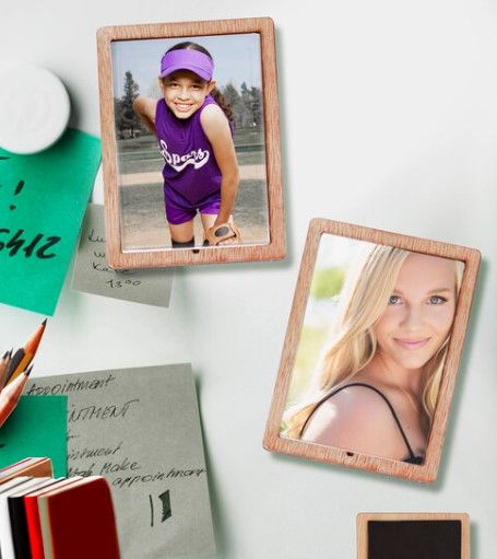 Two wooden framed photos displayed on green surface with office supplies.