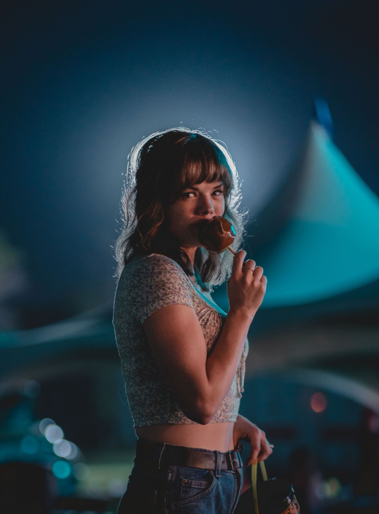 Backlit portrait in festival setting with dramatic blue lighting.