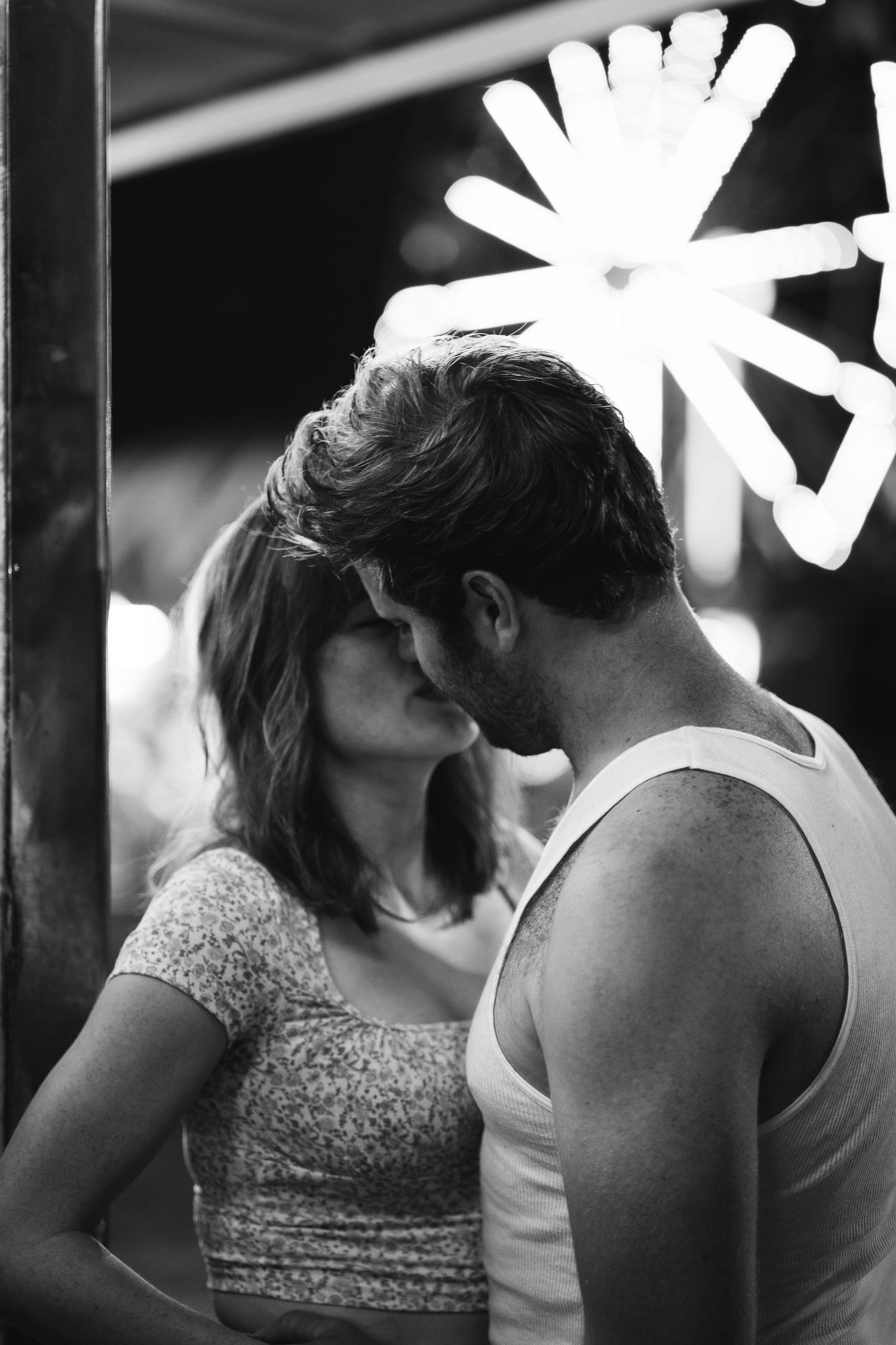 Romantic couple sharing an intimate moment under glowing neon lights at night.