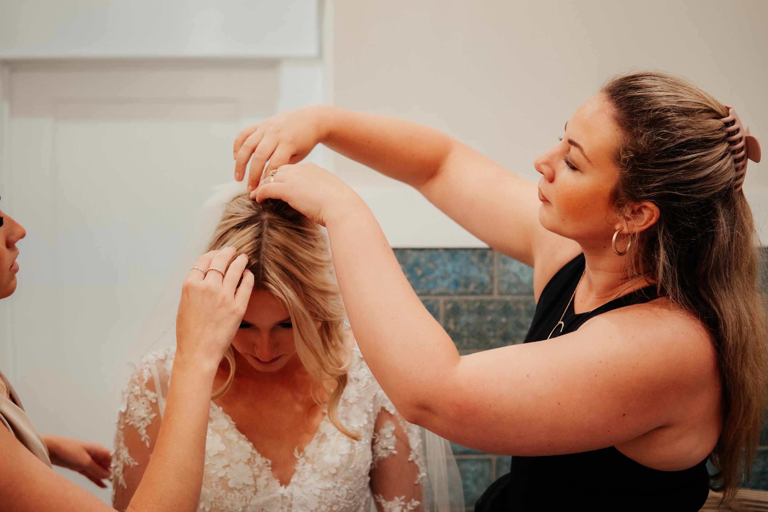 A person styling hair during wedding preparations in an indoor setting.