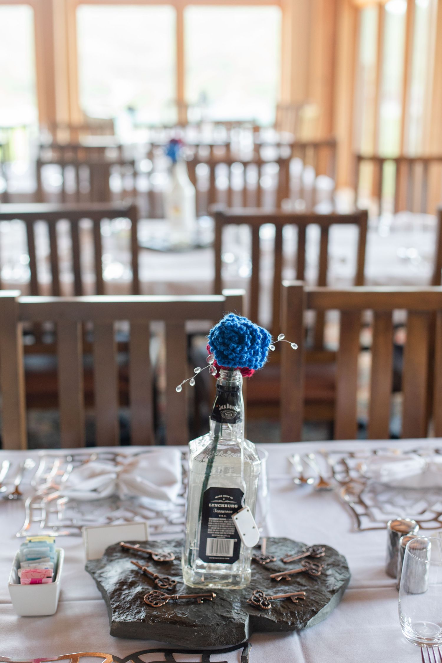 Wedding reception table settings with blue floral centerpieces and wooden chairs.