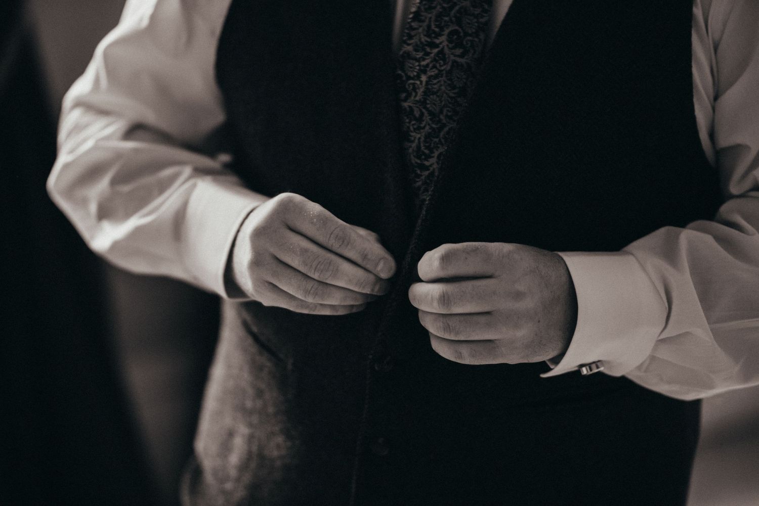 Close-up of hands adjusting formal attire in monochrome.