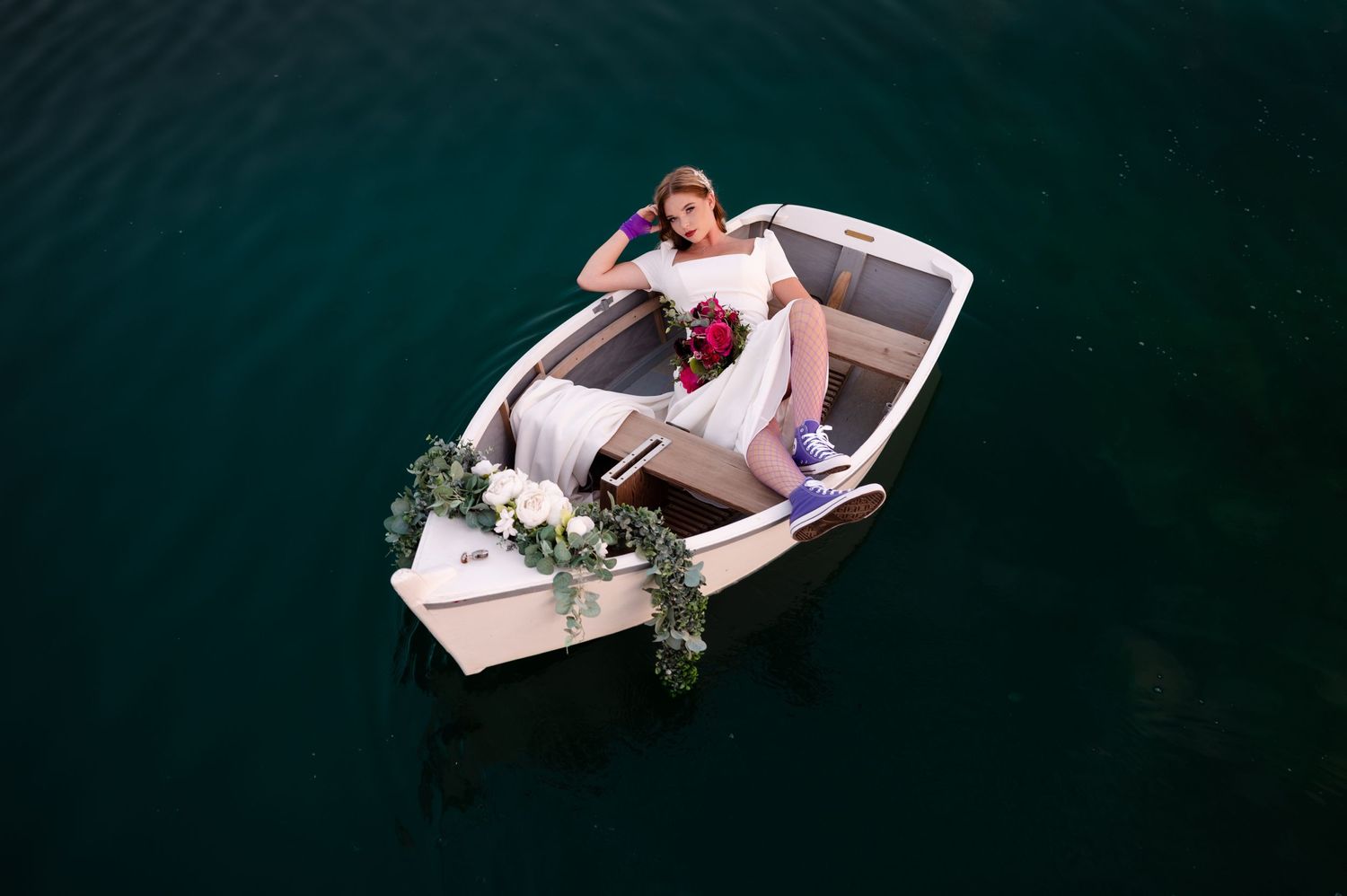 A top-down view of a small white boat decorated with floral arrangements on dark waters.