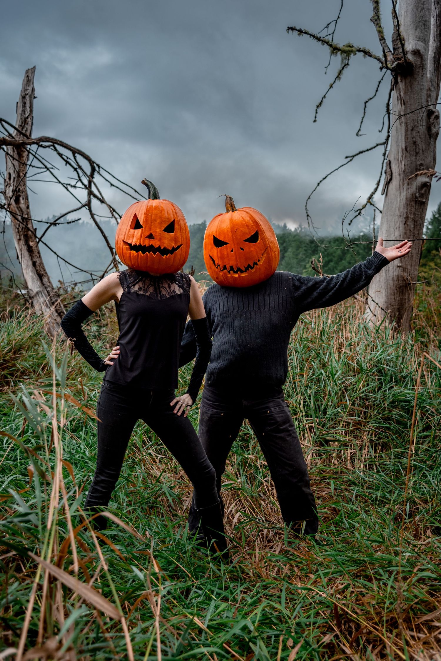Salt Spring Island carved pumpkin heads on a couple dressed in black outdoors.
