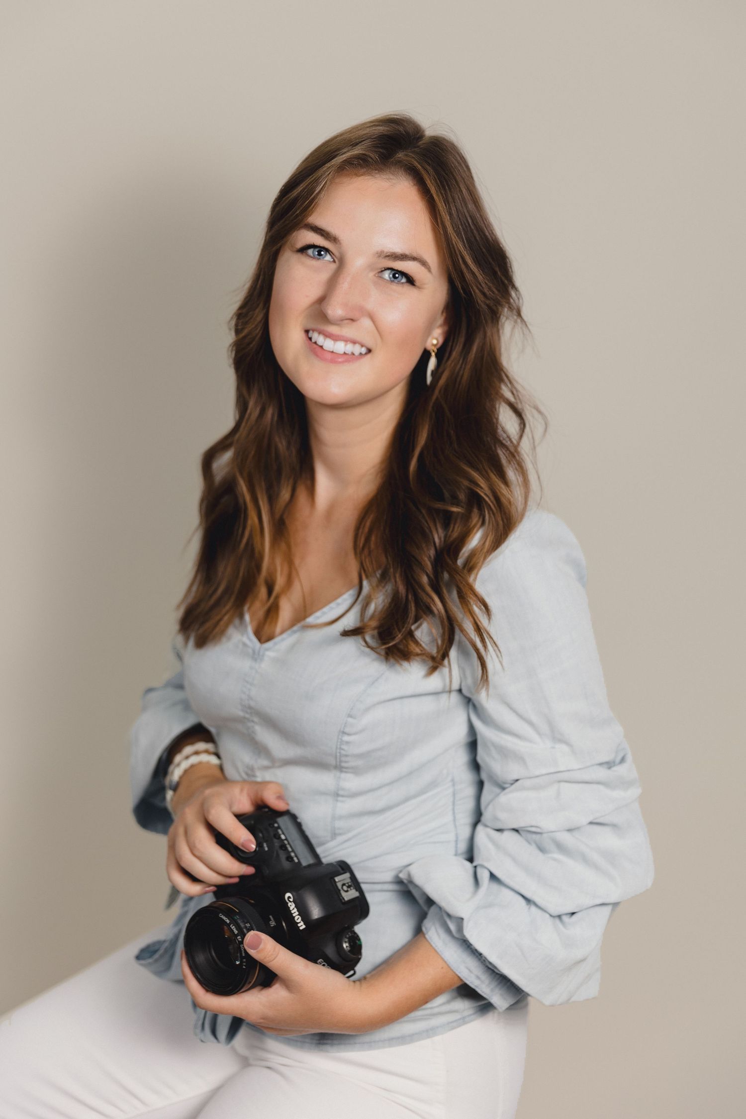 Professional photographer holding camera in studio setting.
