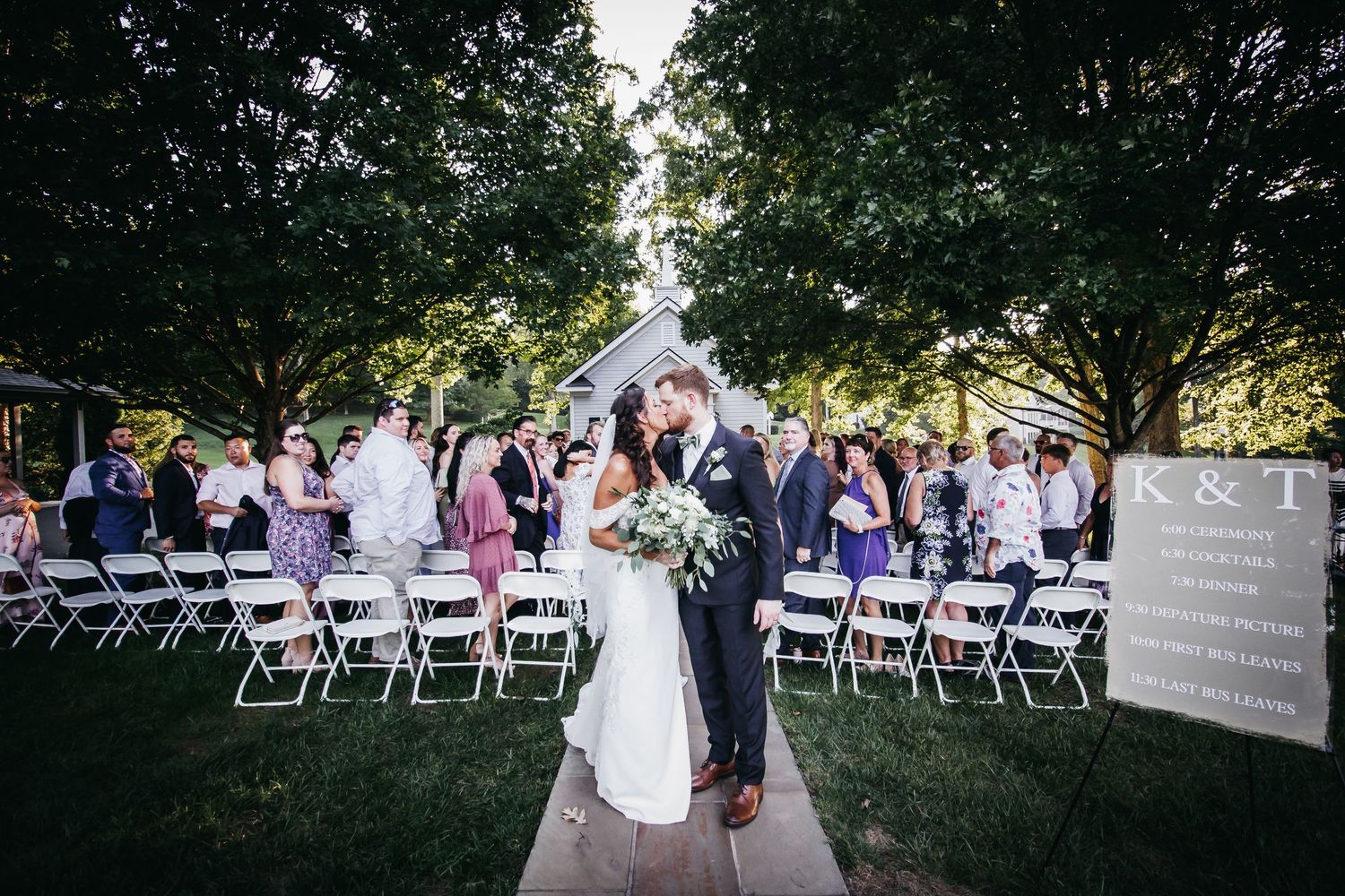 A newly married couple kissing at the altar, surrounded by wedding guests, after the ceremony.