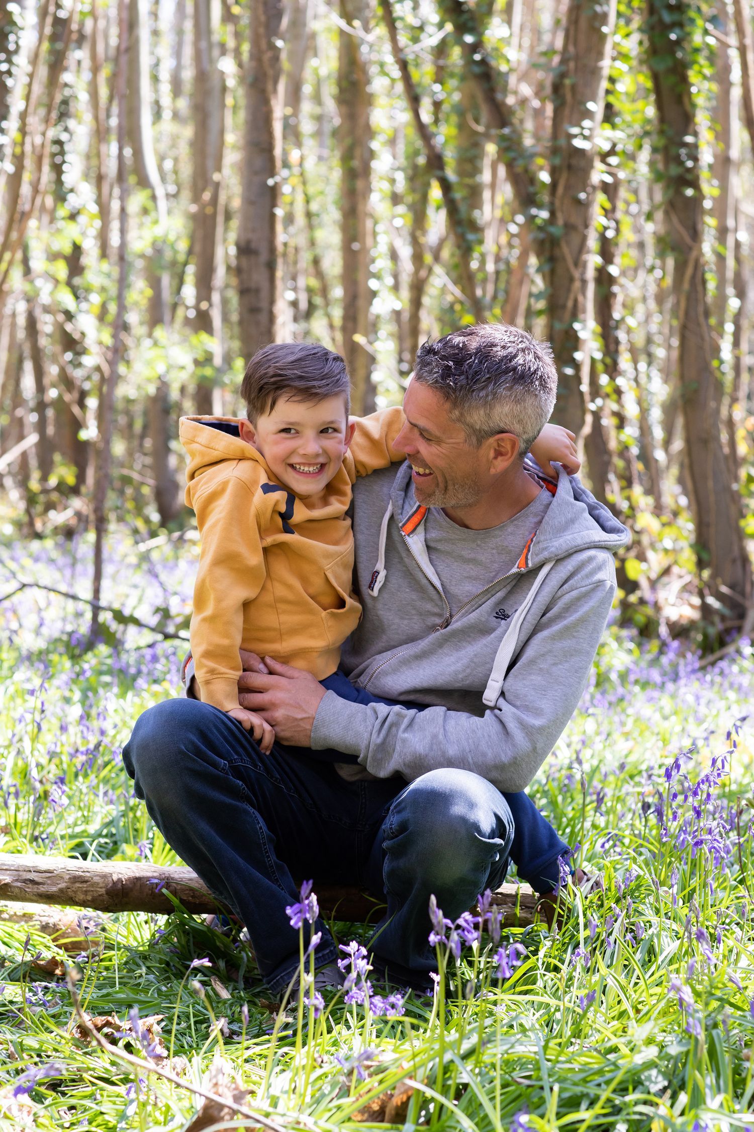 Sweet moment between two people sitting among bluebells in spring woodland.