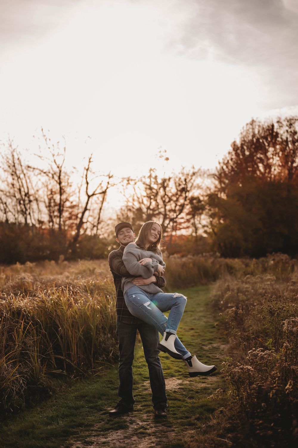 A playful couple enjoying a sunset moment on a nature trail.