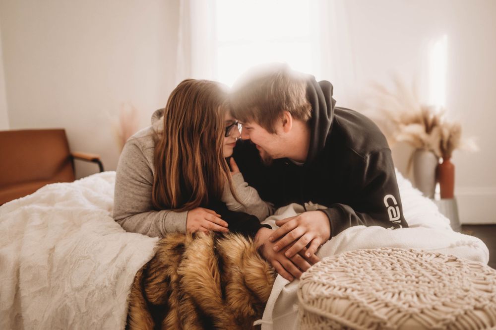 Intimate couple moment on a cozy bed with warm sunlight streaming through the window.