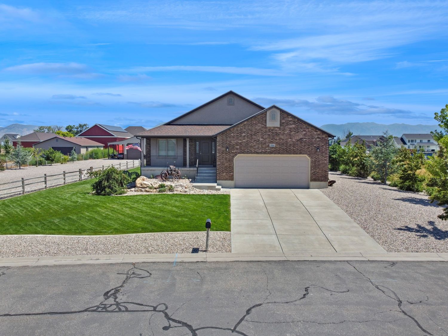 Single-story brick home with a two-car garage, manicured lawn, and concrete driveway on a quiet street.