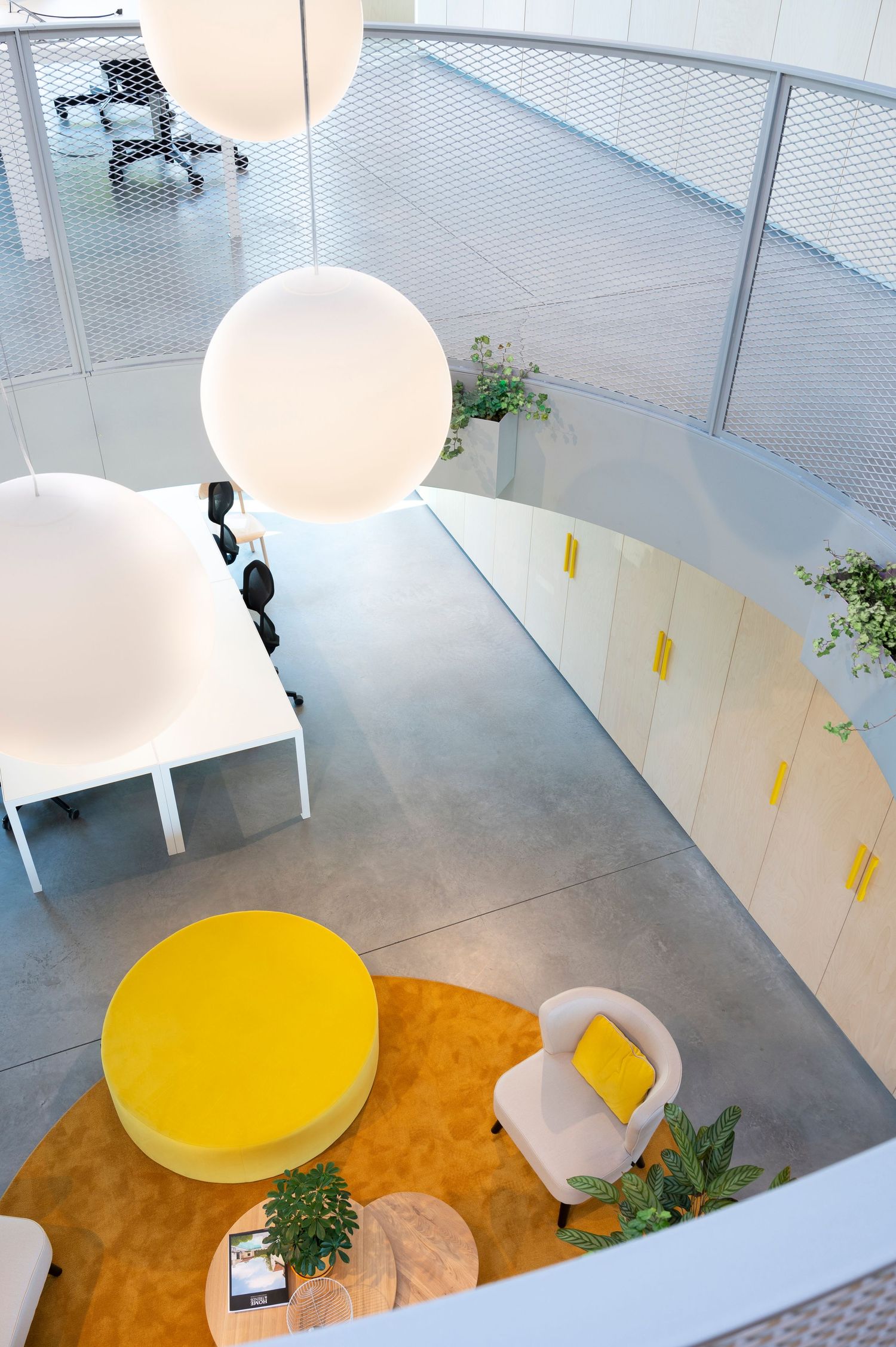 Modern interior space with white walls and yellow circular seating area on brown flooring viewed from above.