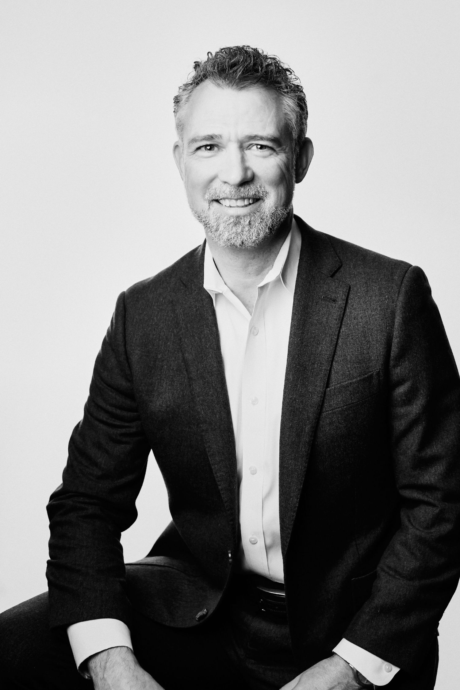 Professional headshot series of person in dark suit jacket against white background.