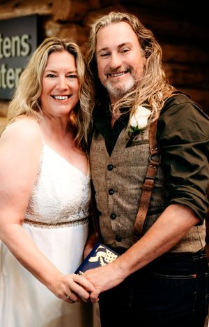 Newlyweds pose together at a rustic wooden lodge after their ceremony.