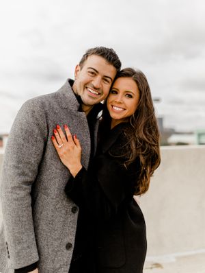 Couple in winter coats sharing joyful moment during outdoor photoshoot.