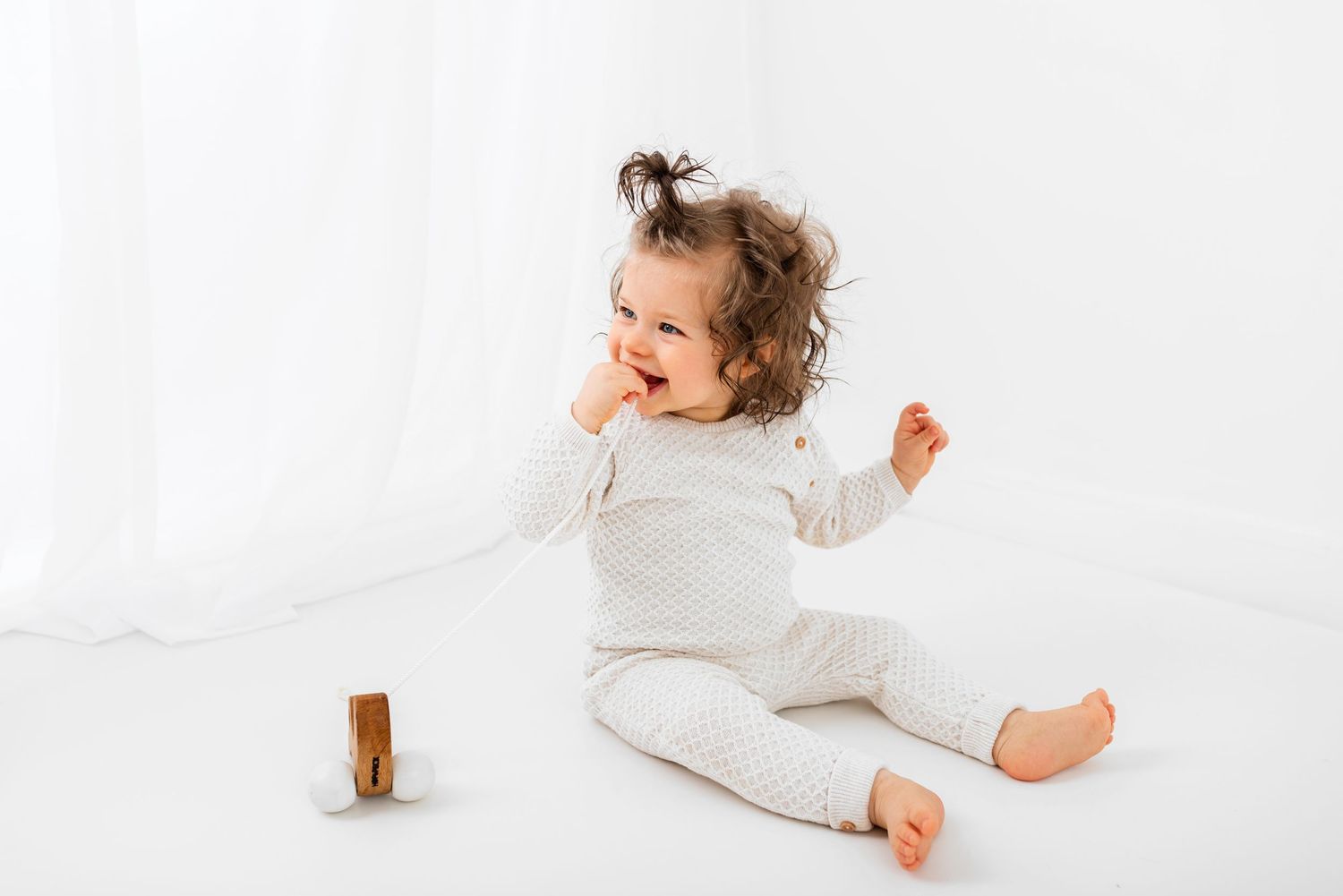 all white baby photos baby sitting in front of a big window