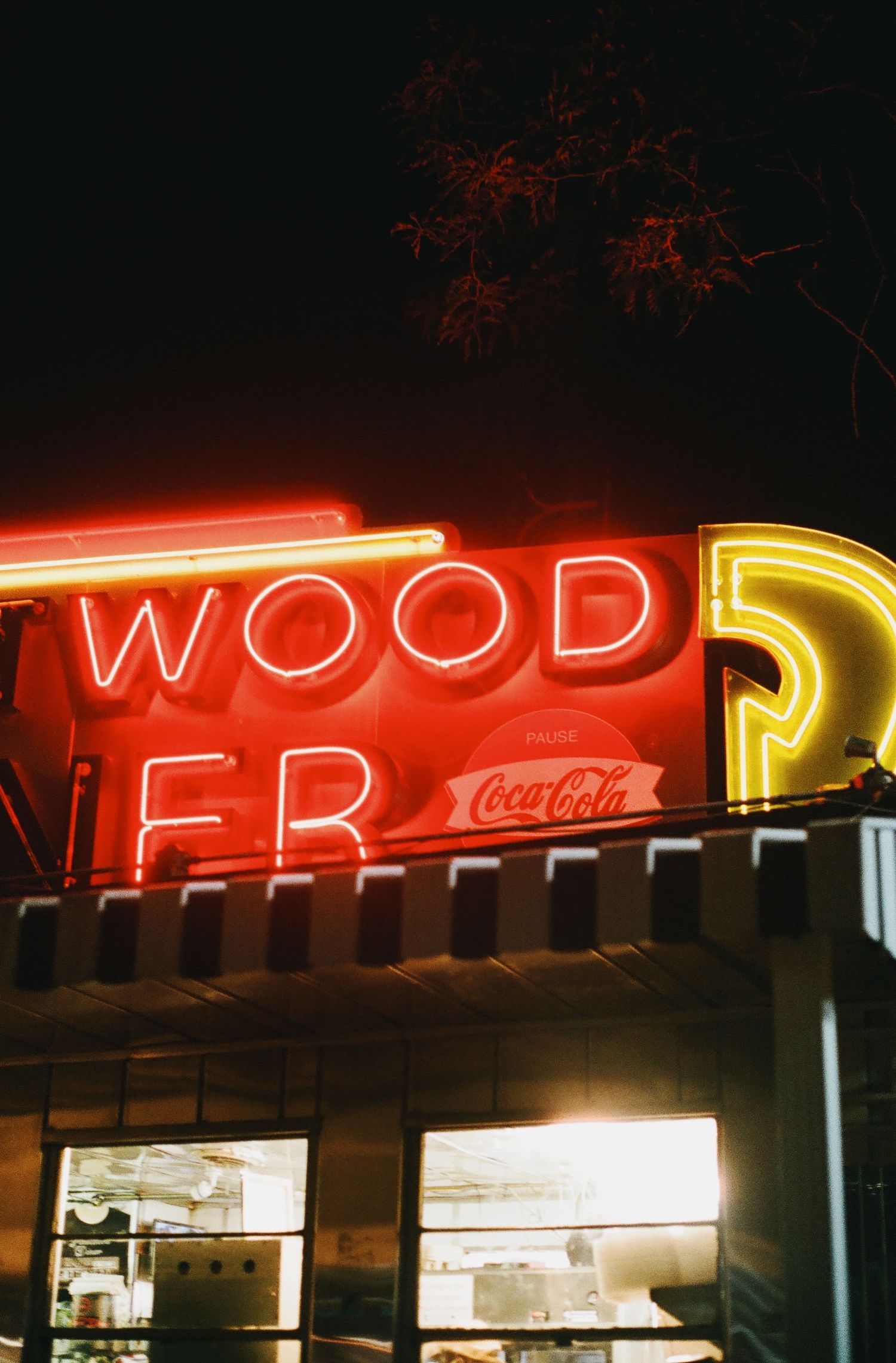 Vintage neon signs illuminating a restaurant facade at night with Coca-Cola branding.