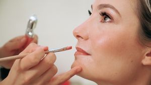 Professional makeup artist applying cosmetics with a brush in preparation for special event.