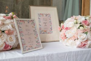 Wedding reception table with pink floral decorations and place cards.