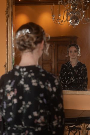 Elegant reflection in mirror showing floral dress details and chandelier lighting.
