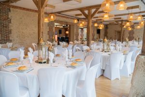 Elegant wedding reception venue with white tablecloths and rustic wooden beams.