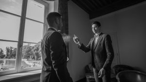 Groomsmen in navy suits share a celebratory moment indoors during wedding preparations.