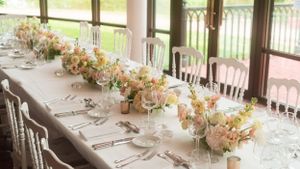 Elegant wedding reception table setting with floral centerpieces and glassware.