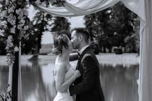 Black and white romantic wedding photos showing a couple embracing by a serene lake with draped decor.
