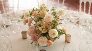 Blush and cream floral centerpieces adorn wedding reception tables.