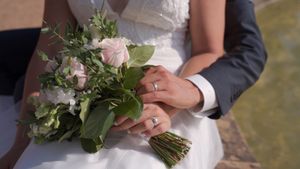 Elegant wedding bouquet with white and pink flowers held against formal attire.