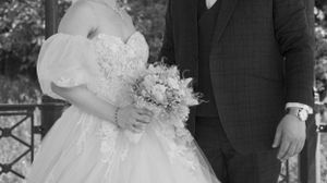 A romantic wedding ceremony moment captured in black and white with guests watching in the background.