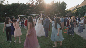 Sunset wedding celebration with guests gathered on a grassy lawn.