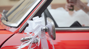 Classic red vintage car decorated with wedding ribbons and bows.