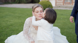 Couple embraces on grassy lawn in elegant wedding attire during outdoor celebration.