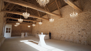Panoramic view of historic stone barn interior with chandeliers and natural lighting.