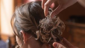 Close-up shot of hands arranging bridal hair accessories in warm lighting.