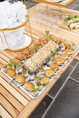 Gourmet mini burgers arranged on wooden serving platters at a wedding reception.