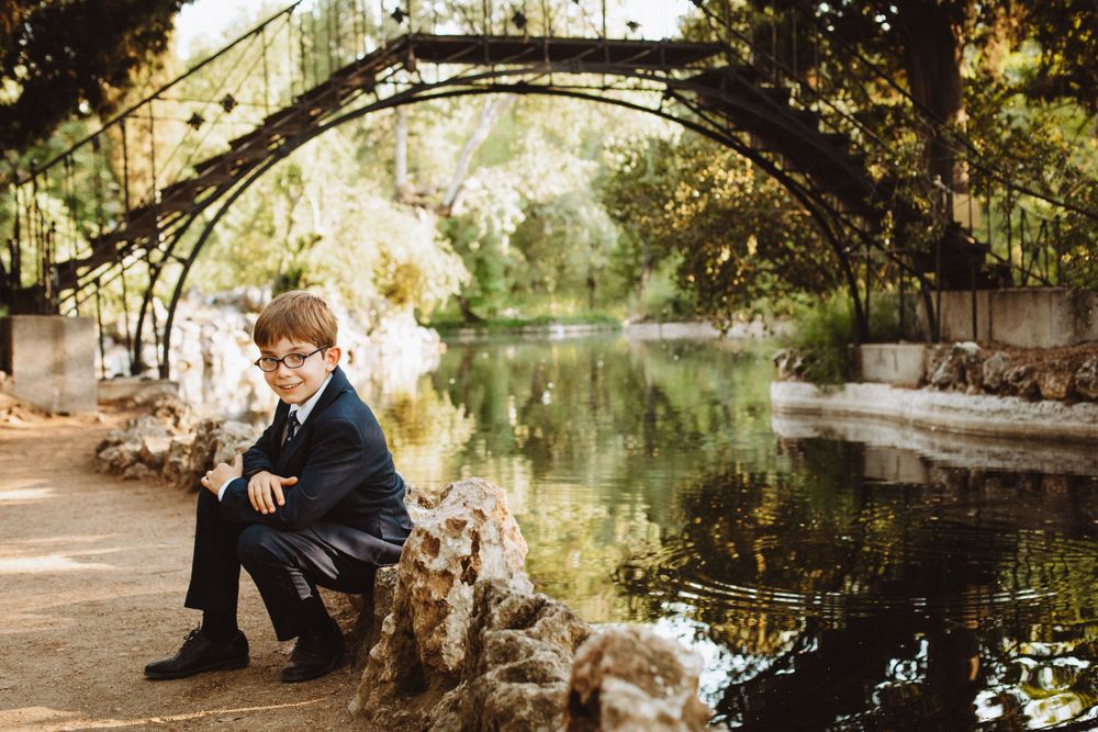 Artistic portrait by stone bridge over reflective water.
