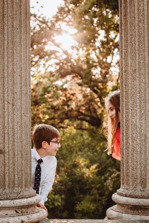 Playful peek between classical stone columns in golden sunlight.