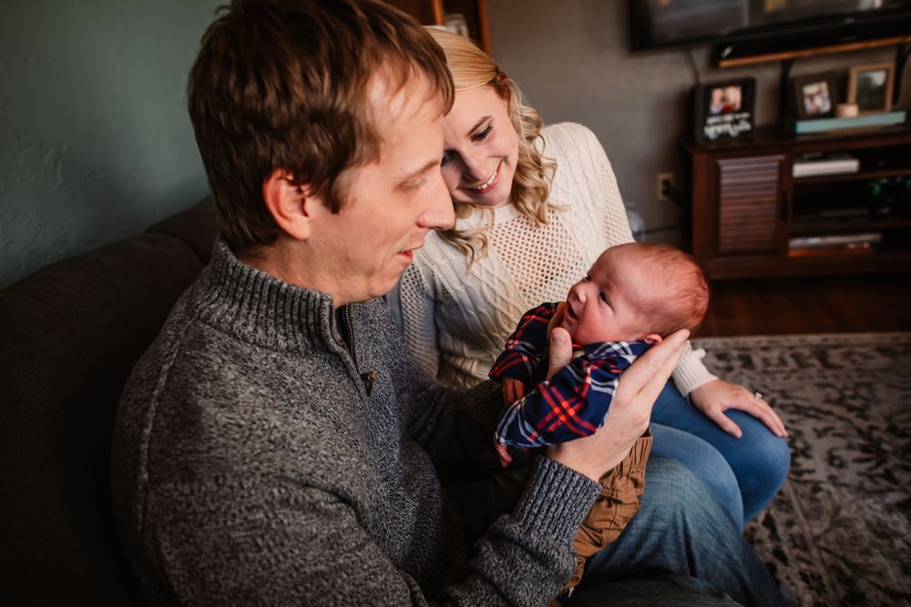 An intimate family moment on the couch with a newborn baby in casual attire.