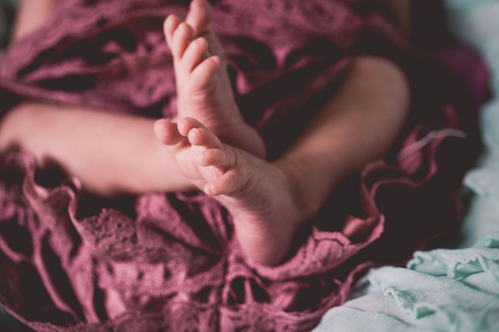 Close-up of tiny baby feet against burgundy fabric.