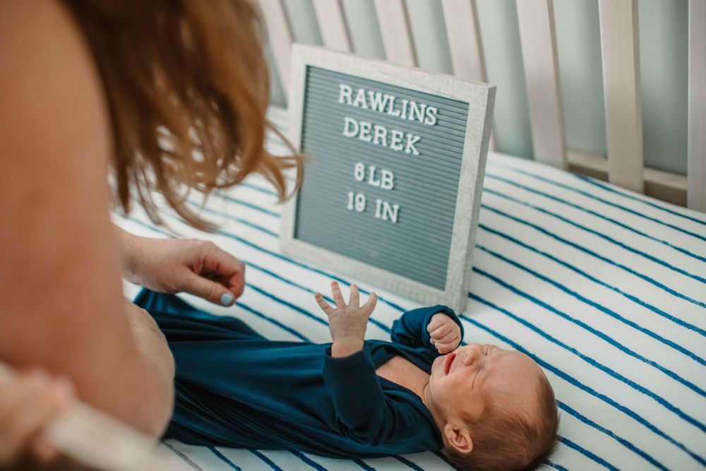 Letter board and striped bedding in nursery with text showing measurements.