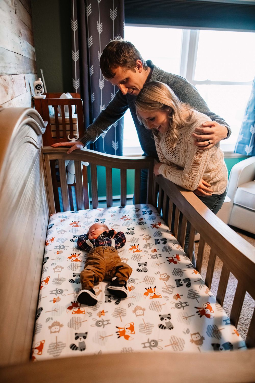 Looking down at a baby in a crib with adorable animal print bedding.