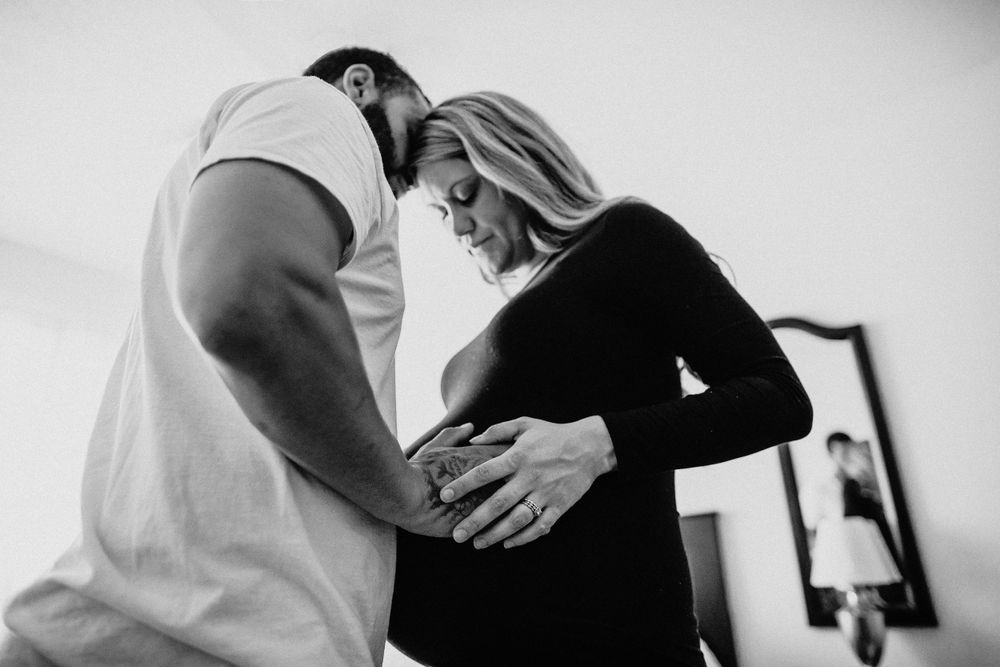 Black and white intimate maternity portrait showing gentle embrace.
