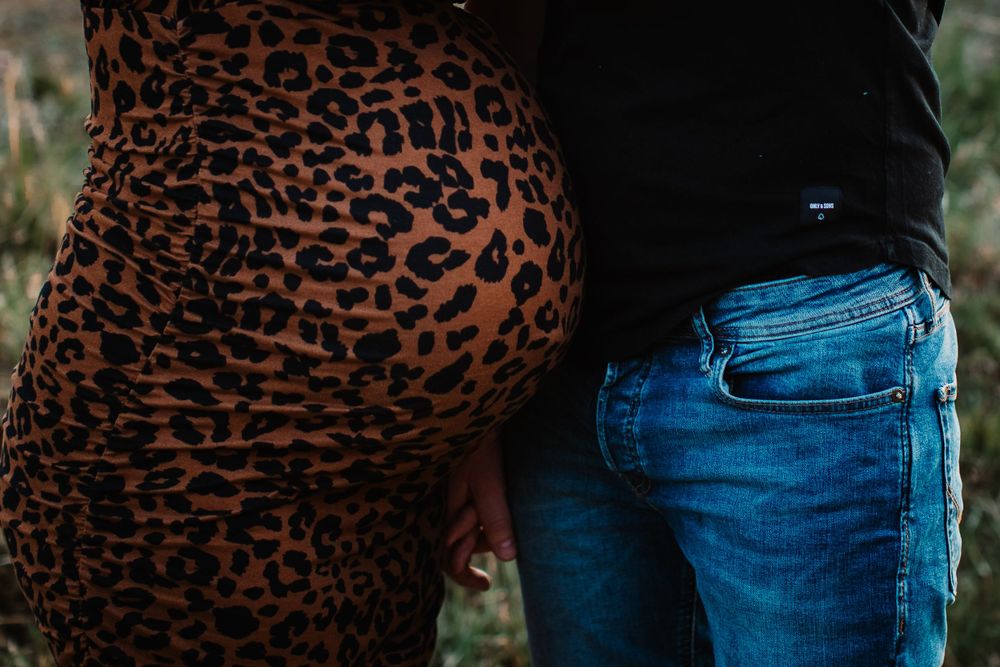 Close-up shot of leopard print maternity dress against denim in outdoor setting.