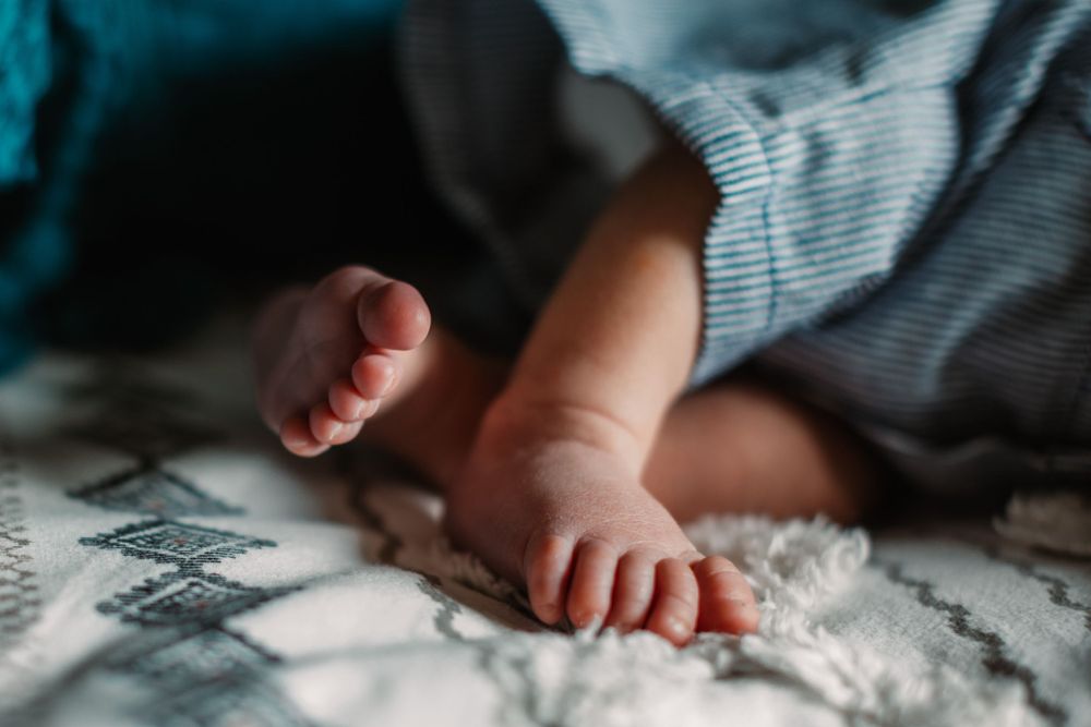 Close-up of tiny baby feet on soft textured blanket in natural lighting.
