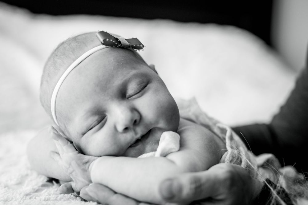 Black and white portrait of sleeping newborn with delicate headband.