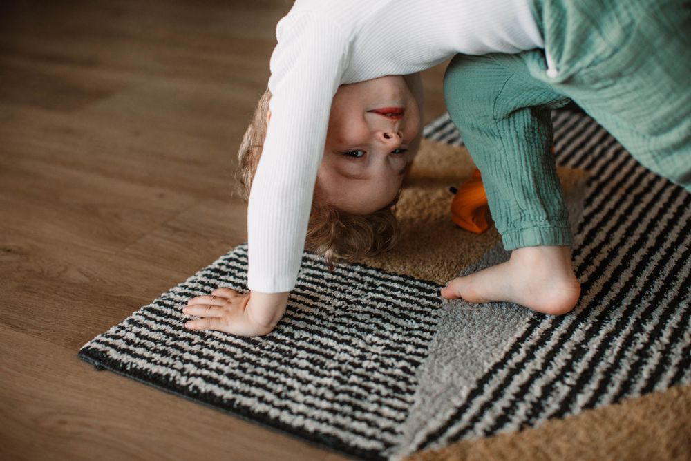 Child playing on patterned rug showing playful movement.