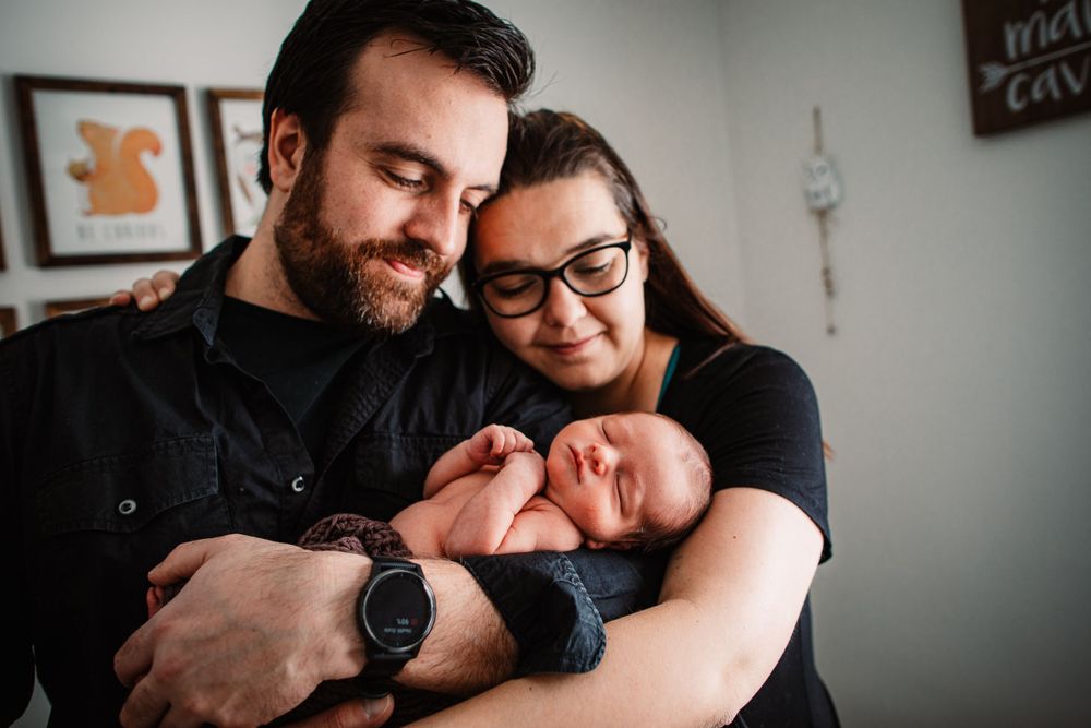 A tender family moment as parents gaze lovingly at their newborn baby in a cozy home setting.