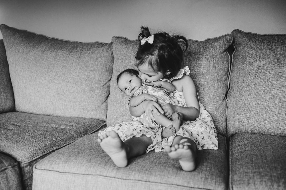 Black and white photo of tender family moment on a comfortable couch.